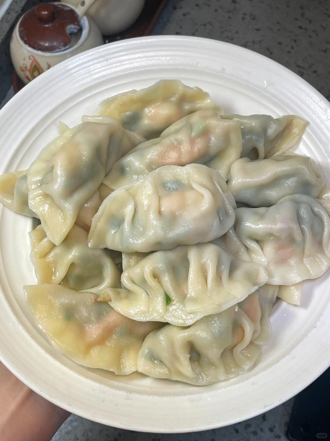 Pale boiled dumplings with folded edges on a white plate.